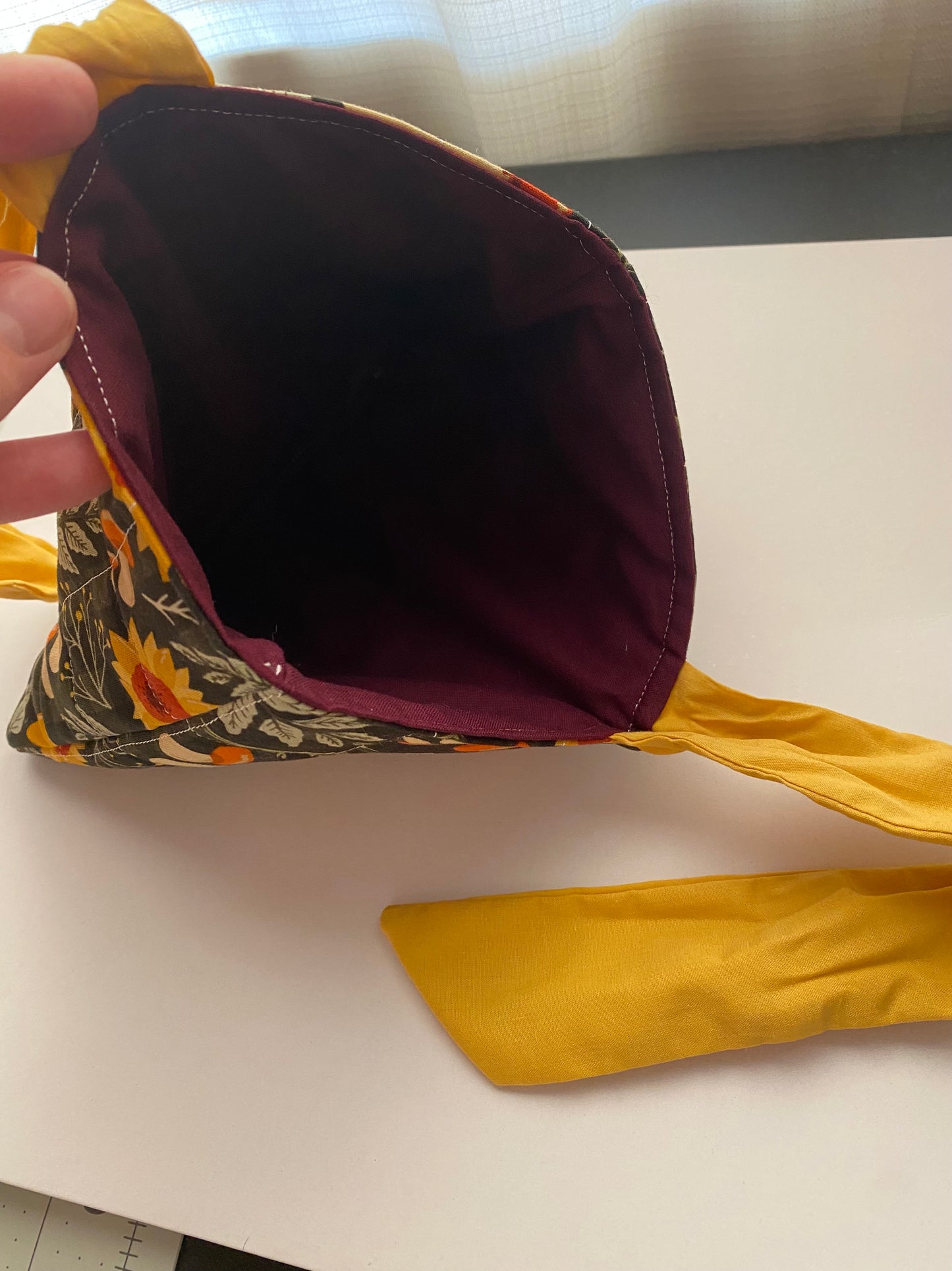 Close-up of book sleeve with a autumn floral pattern and yellow bow with dark purple liner.