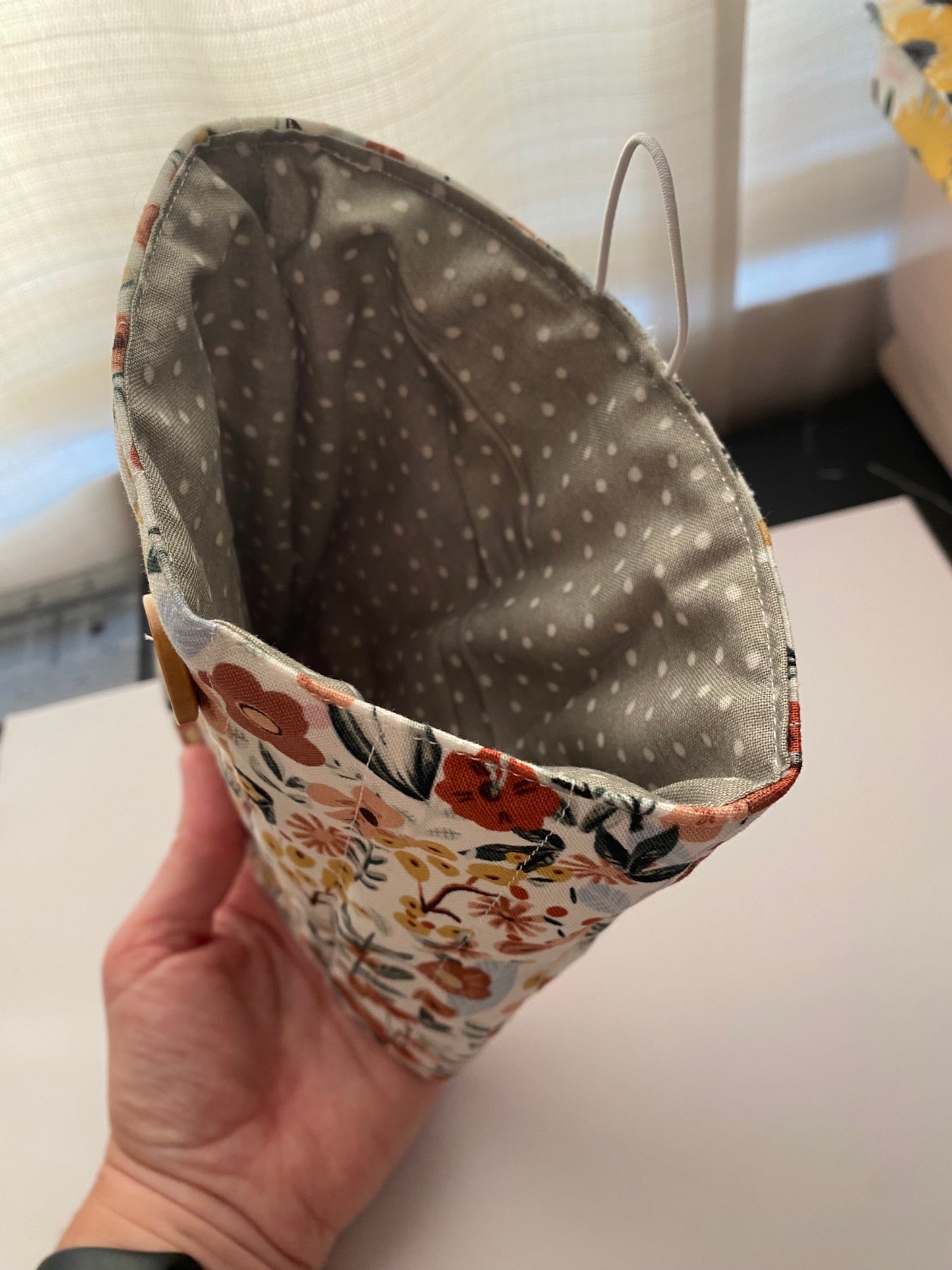 Hand holding a fabric book sleeve with floral and polka dot patterns.