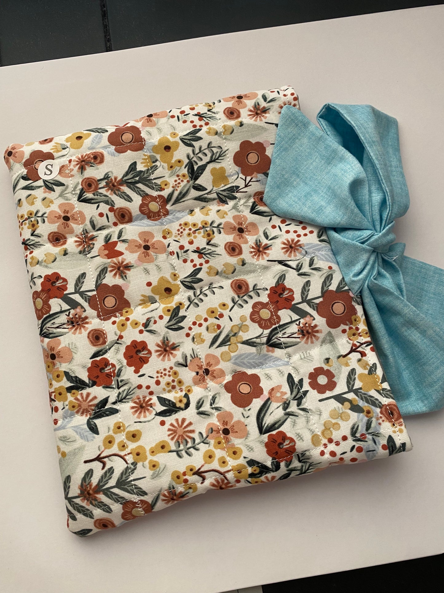 Floral-patterned fabric with a blue bow on a light background