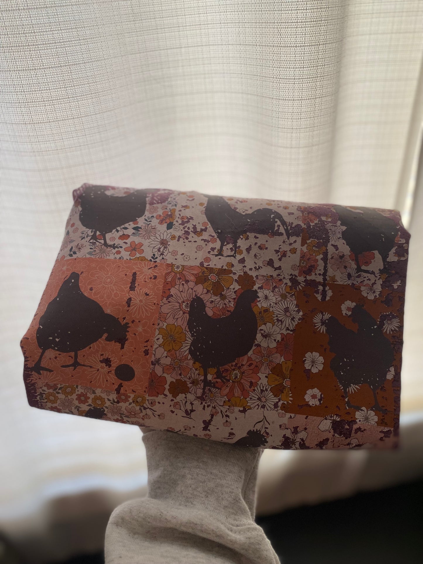 Fabric with chicken pattern held by a person against a neutral background