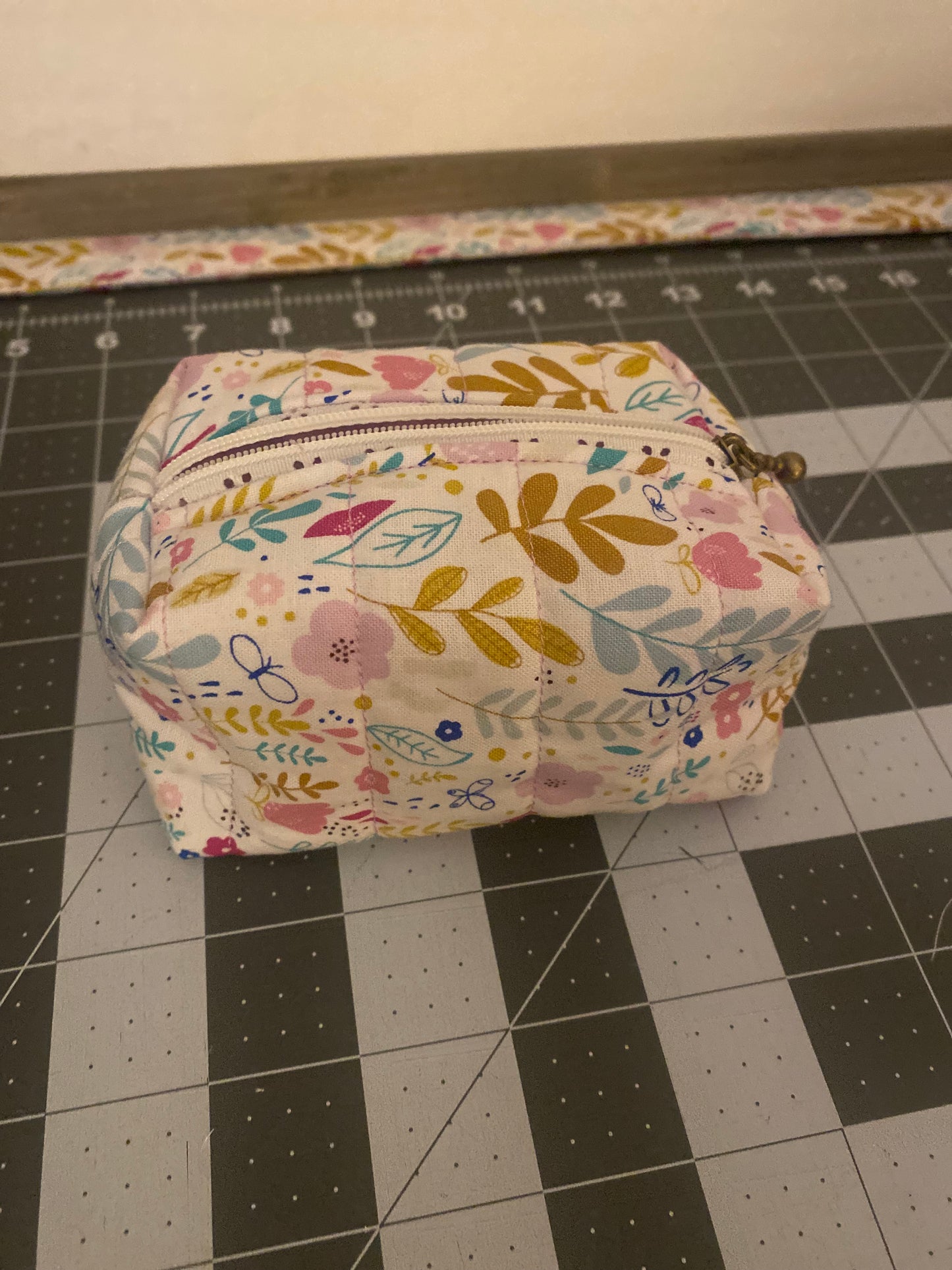 Floral-patterned pouch on a black and white grid background
