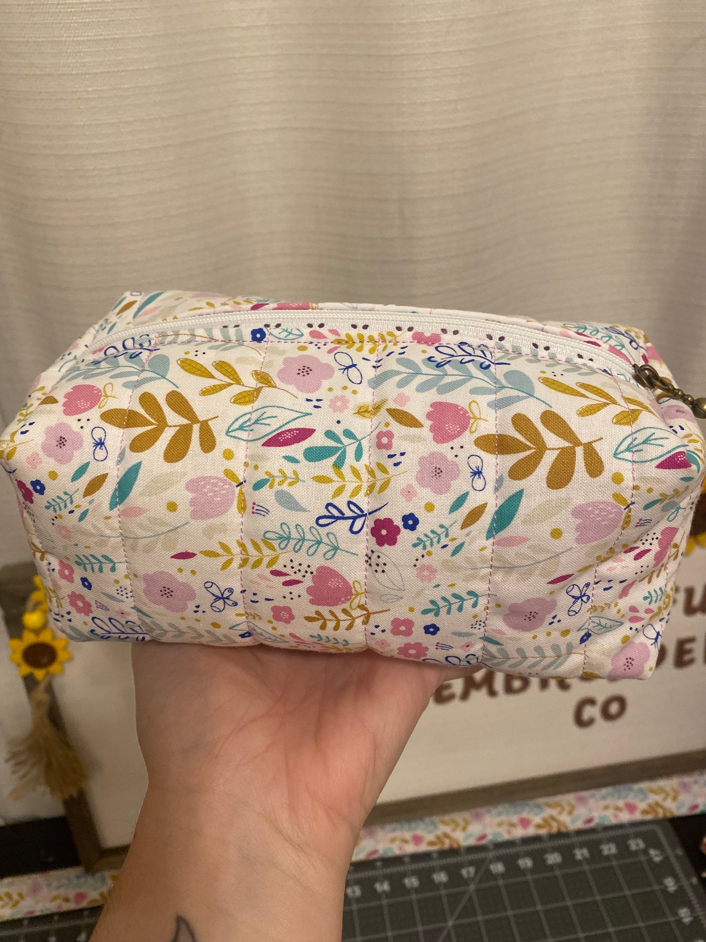 Floral-patterned pouch held by a hand with a neutral background