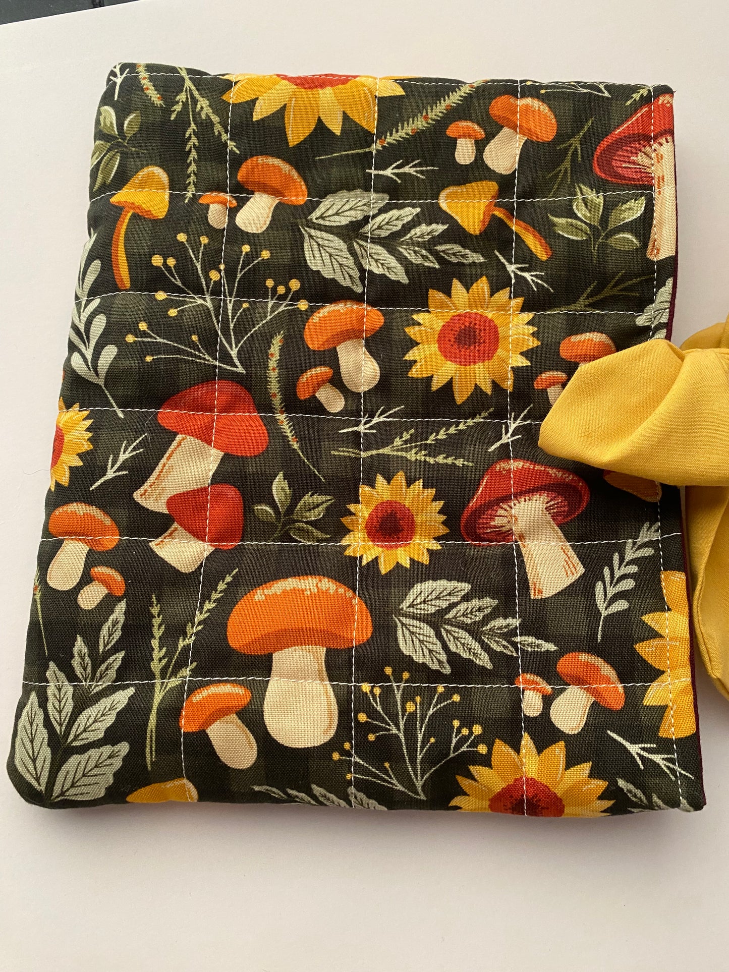Floral and mushroom patterned pouch with a yellow bow on a white background