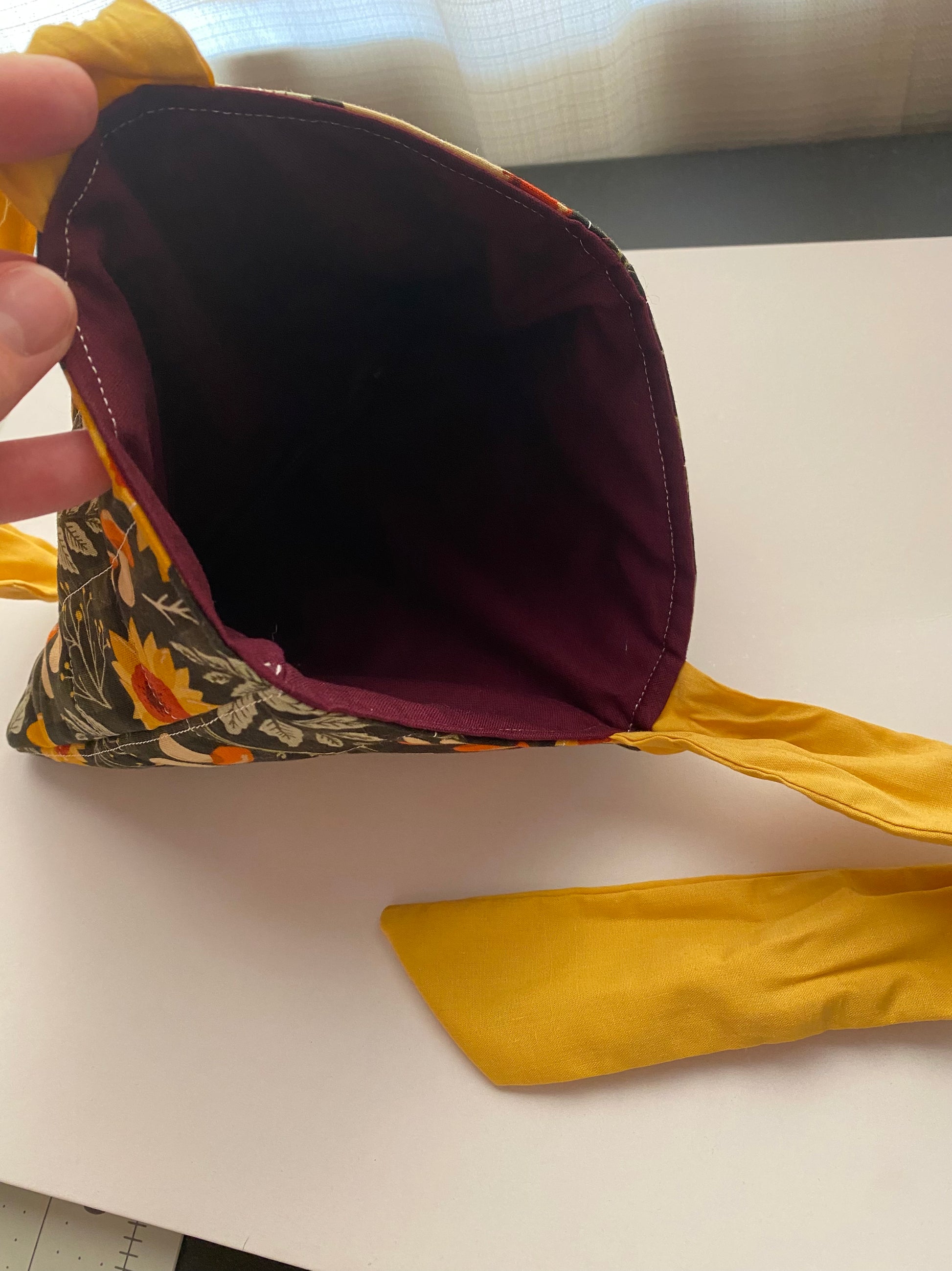 Close-up of book sleeve with a  autumn floral pattern and yellow bow with dark purple liner.