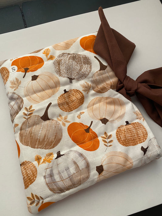 Fabric with pumpkin pattern and brown bow on a white surface