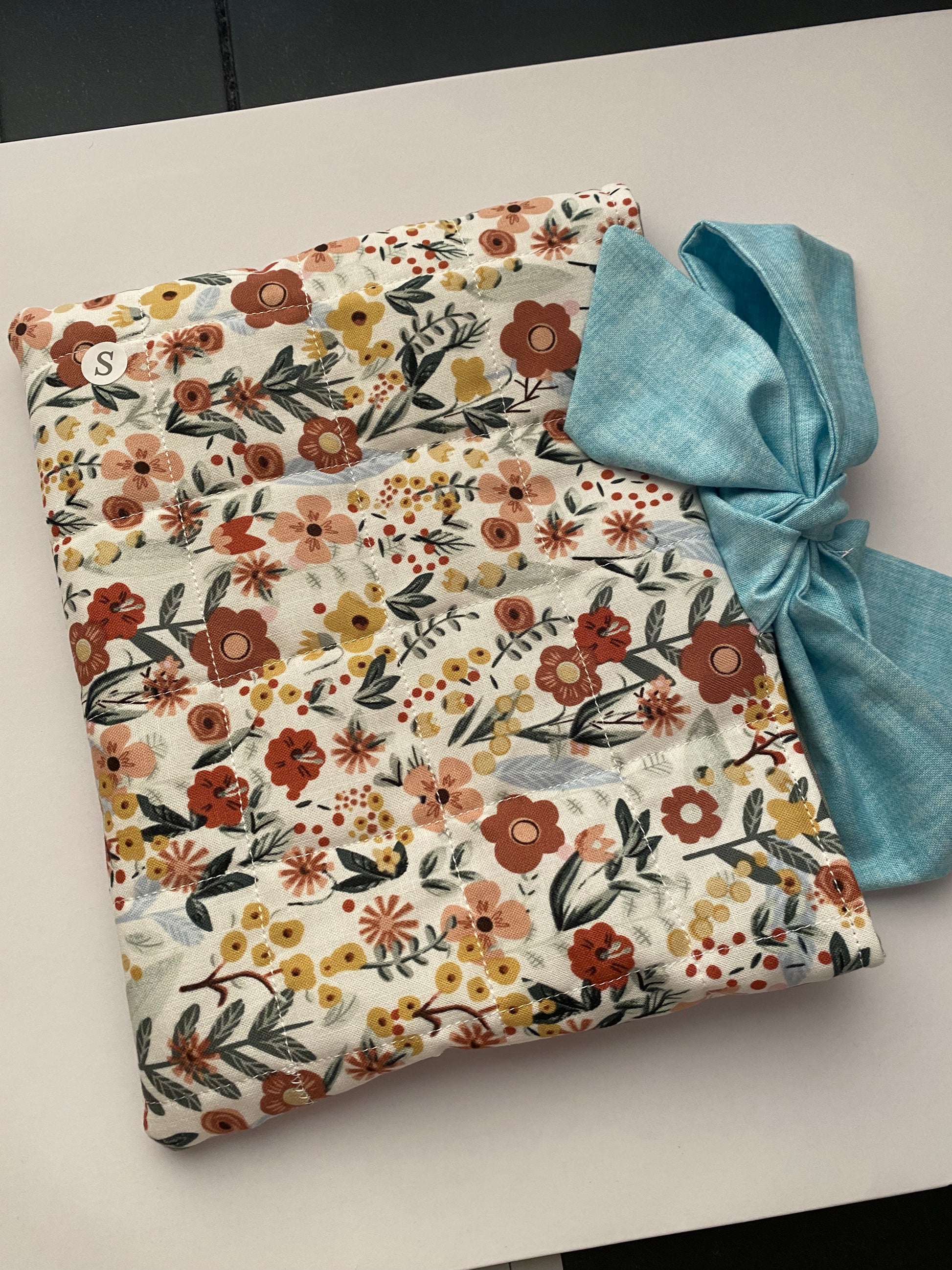 Floral-patterned fabric with a blue bow on a light background
