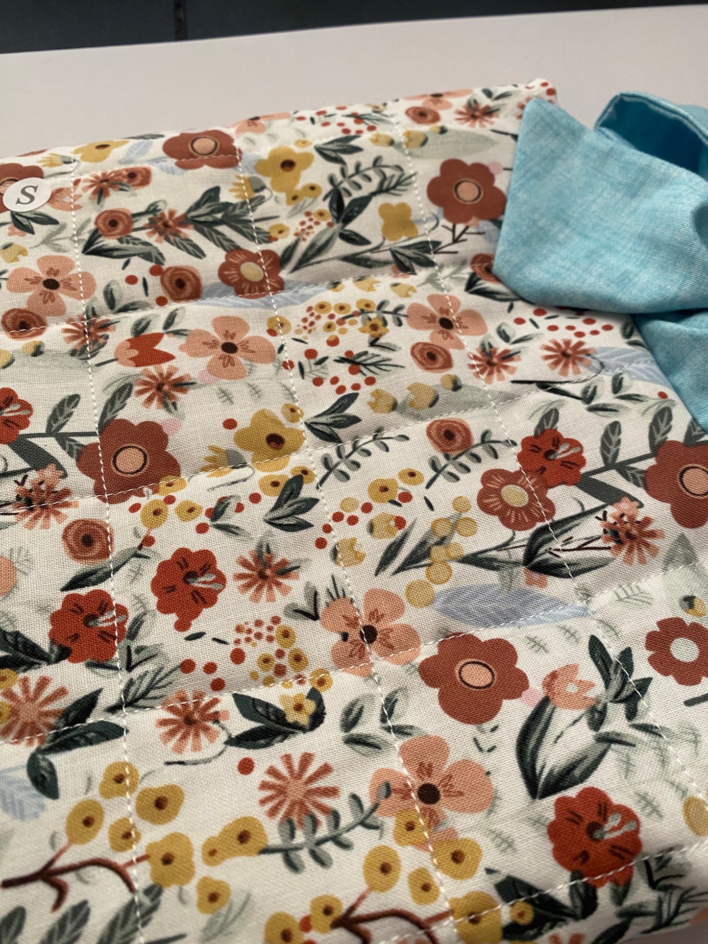 Floral patterned fabric with a blue bow on a neutral background