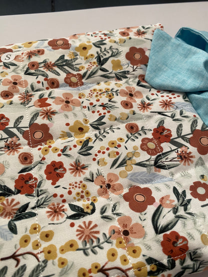 Floral patterned fabric with a blue bow on a neutral background