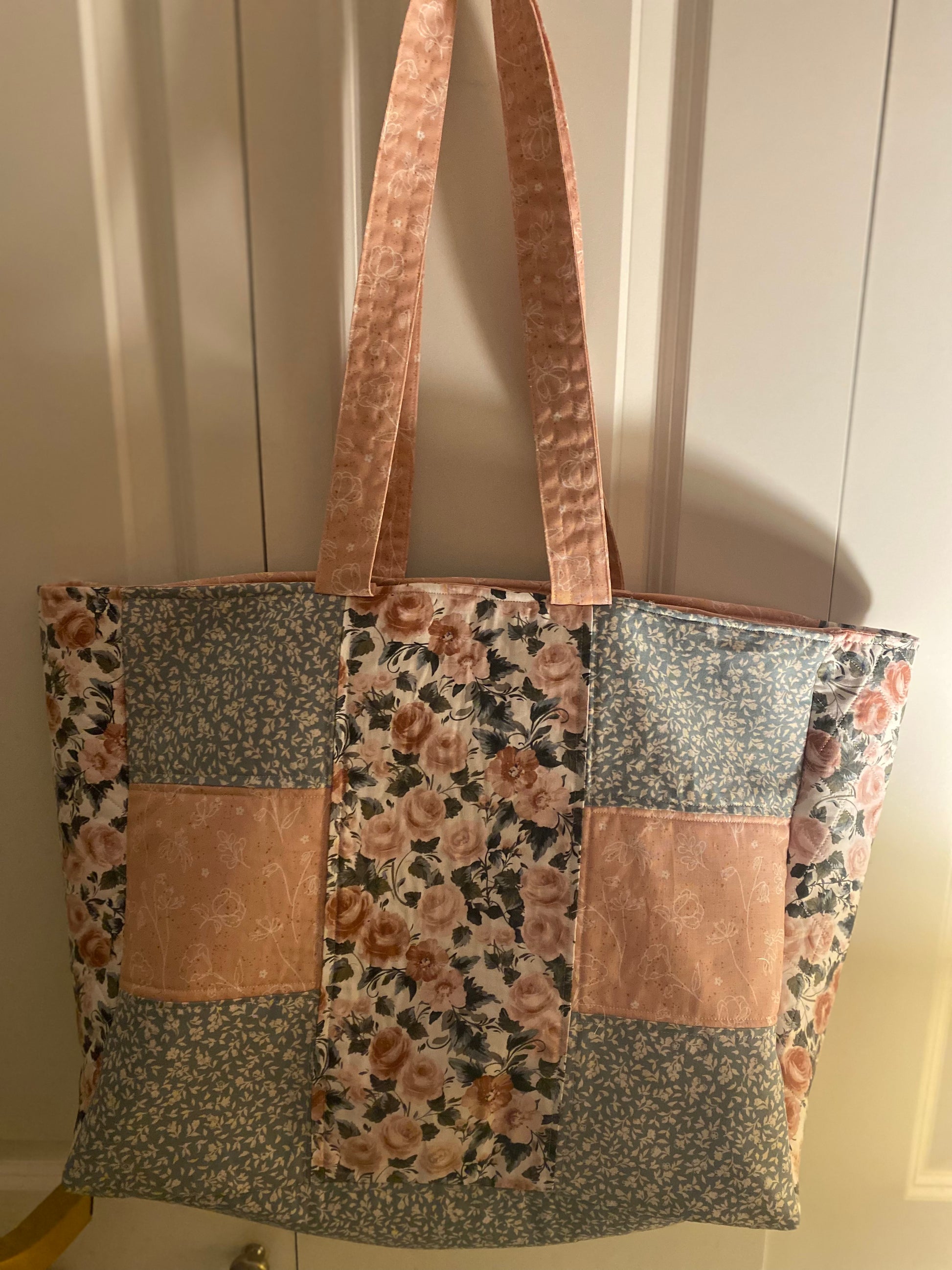 Patchwork tote bag with floral and floral-patterned fabric sections on a neutral background.