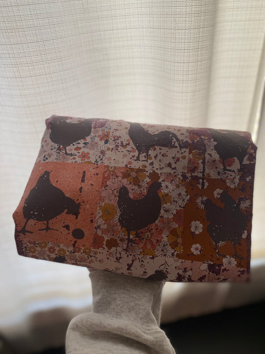 Fabric with chicken pattern held by a person against a neutral background