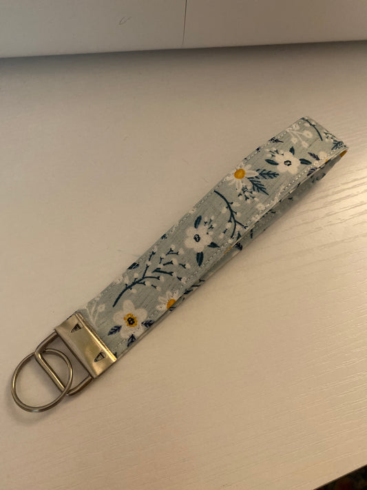 Floral patterned keychain strap with metal clasp on a plain background