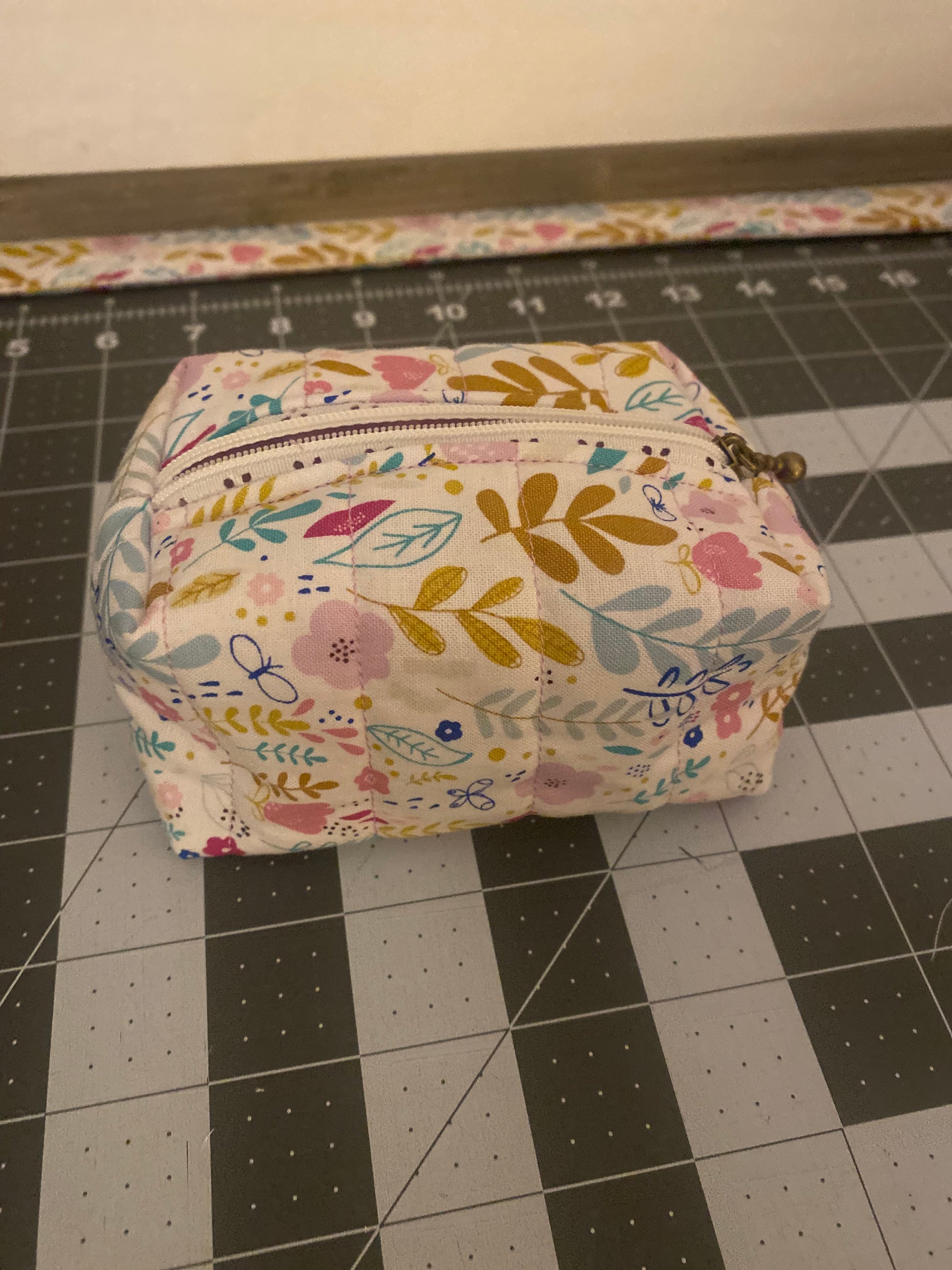 Floral-patterned pouch on a black and white grid background
